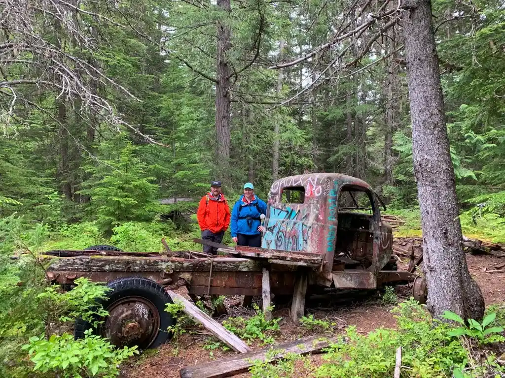 Two hikers next to an abandoned truck near Whistler, BC