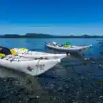 Three kayaks on the beach in the Johnstone Strait on Vancouver Island in British Columbia, Canada. Go kayaking in the Johnstone Strait