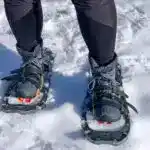 Close up of a a person wearing insulated hiking boots with snowshoes. The best boots for snowshoeing