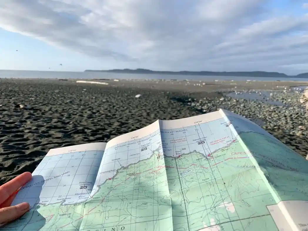 A hiker hold a map on a beach hike - A map is one of the 10 essentials you should bring on every hike and it's helpful for trip planning