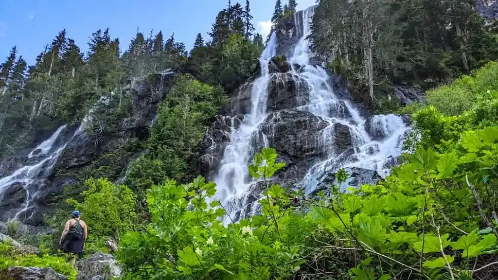 A hiker admires the base of Della Falls from the Della Falls Trail