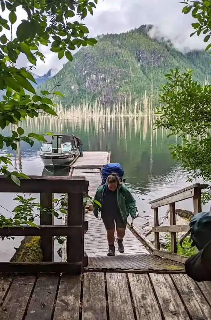 A hiker walks up the stairs from the Della Falls Trailhead dock