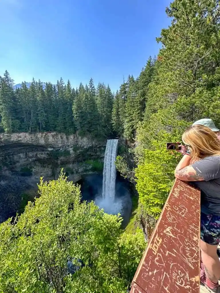 A woman takes a photo of Brandywine Falls