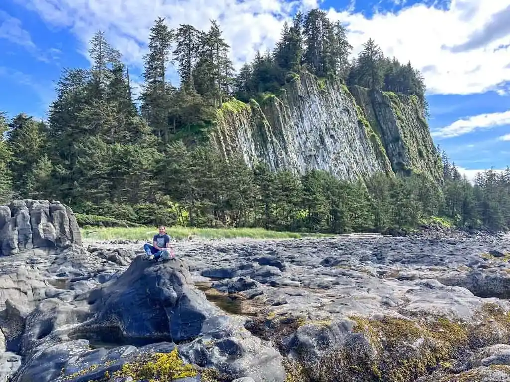 A man sits on a rock in front of the cliffs at Tow Hill