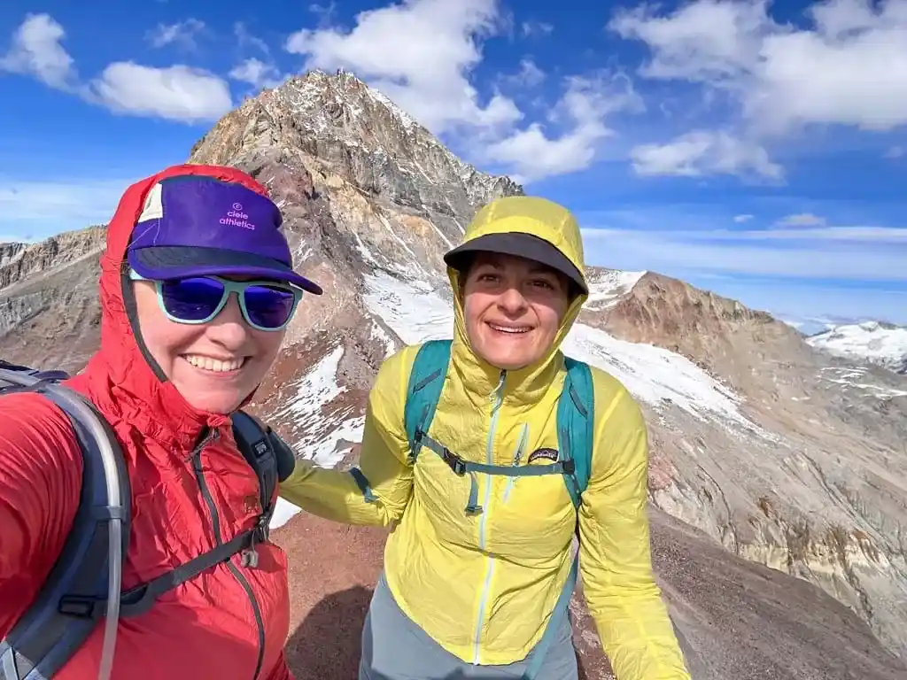 Taryn poses with a friend on the summit of Diamondhead Peak in Squamish while wearing a Ciele GoCap