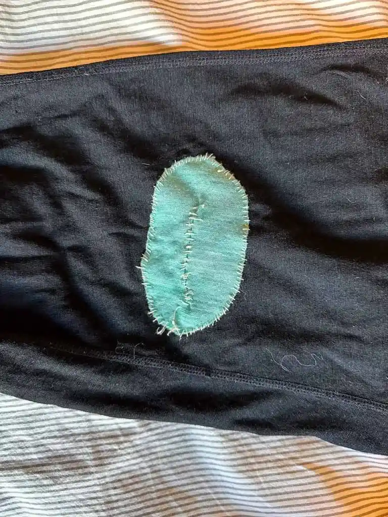 A hand sewn patch on a pair of Merino wool base layer bottoms
