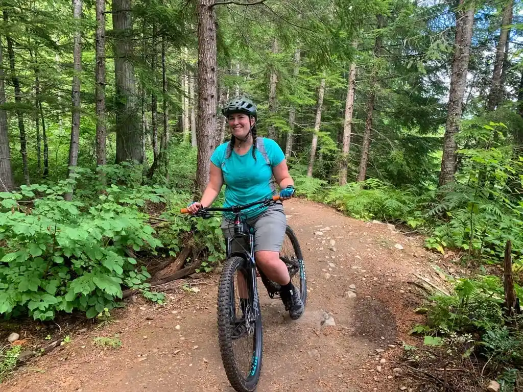 A woman wearing a Merino wool shirt poses on a mountain bike