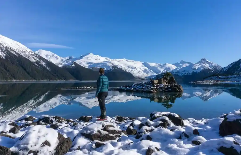 A woman wears a Merino wool jacket in the winter at Garibaldi Lake