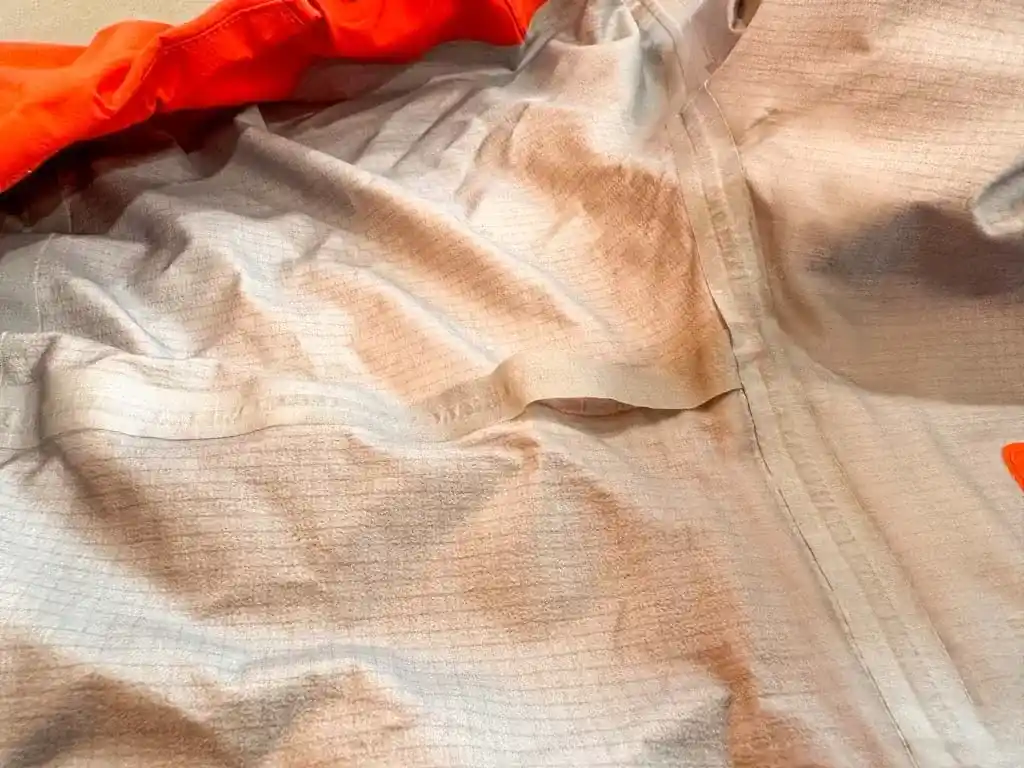 A piece of seam tape peeling off inside a rain jacket. Why do rain jackets wet out? Because the seam sealing fails. 