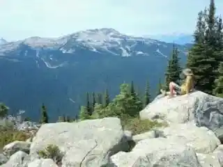 A hiker sits on a rock and enjoys the view on the Blackcomb trails