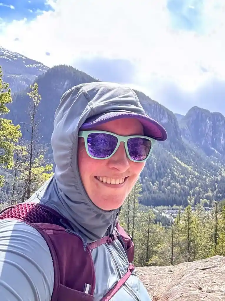 A close up of a hiker wearing a Black Diamond Alpenglow Pro Sun Hoodie with the hood up