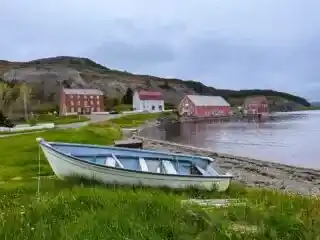 A boat sits in the grass in front of the Lester-Garland Premises, one of the best things to do in Trinity, Newfoundland
