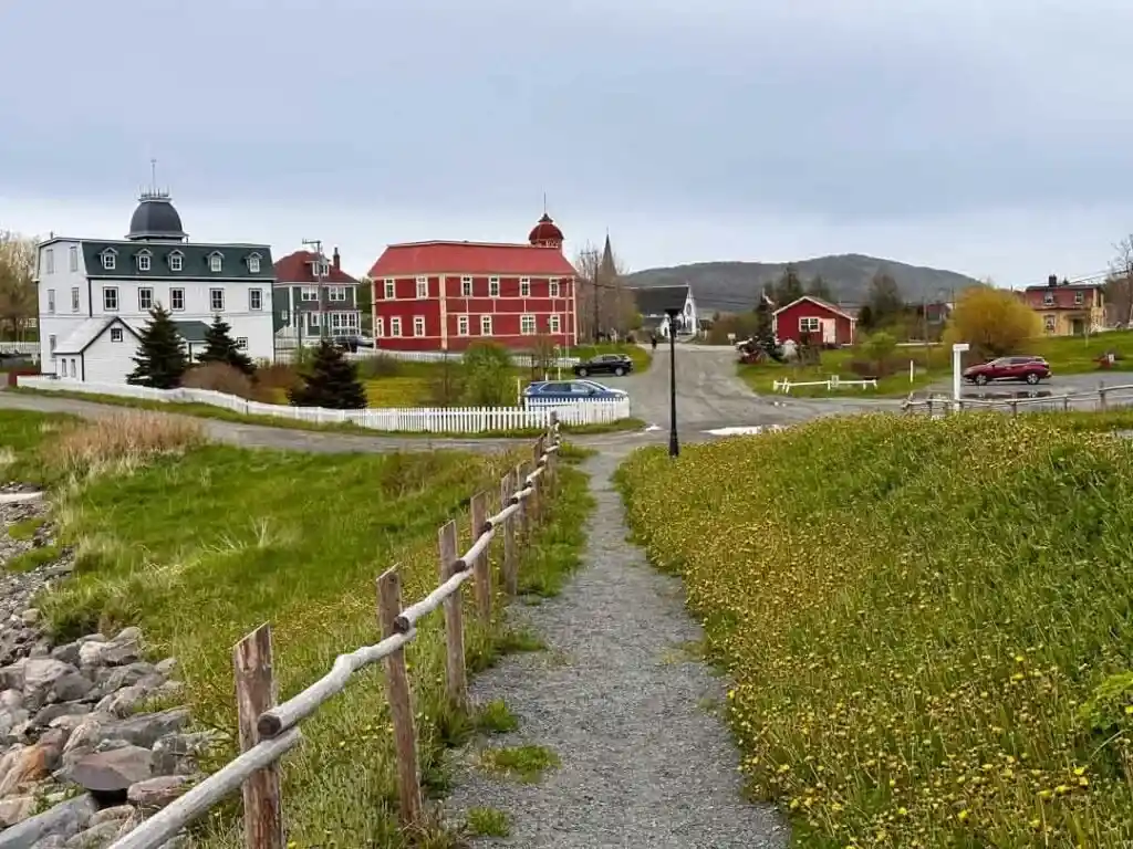 Looking down a flower-lined path towards historical buildings in Trinity