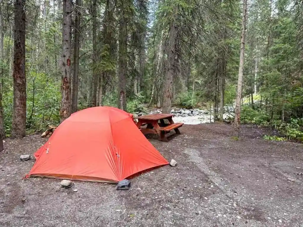 Orange Big Agnes Copper Spur tent at a drive-in campsite with a picnic table. 
