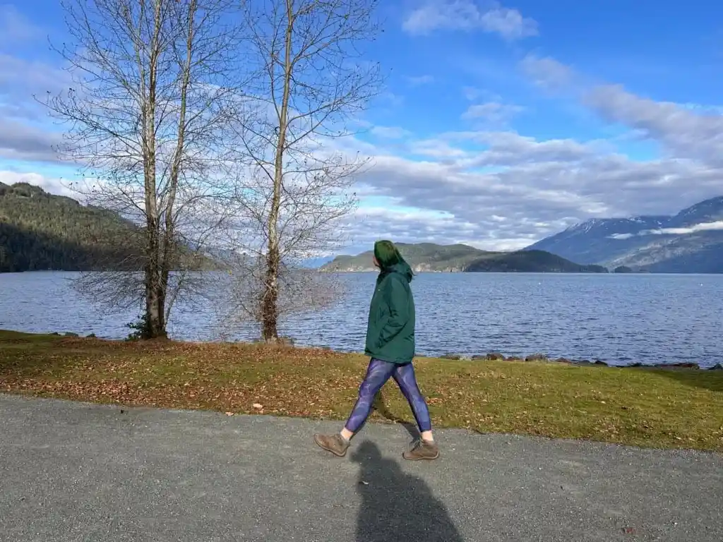 A woman in a green coat walking along the Esplanade in Harrison Hot Springs