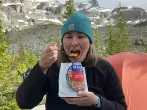 A hiker eats a Mountain House backpacking meal at a campsite. It is one of the best backpacking meals she reviewed.